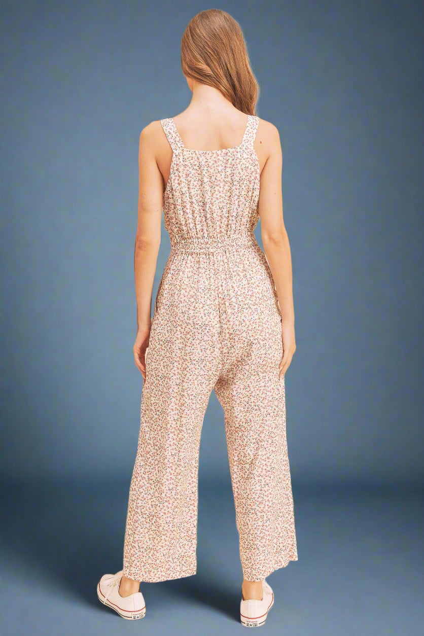 Woman wearing a floral jumpsuit against a beige background