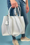 Model is carrying a large satchel with removable colorful woven strap. 