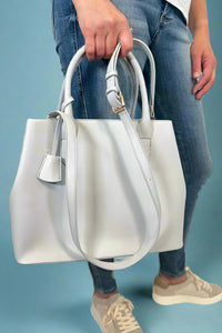 Model is carrying a large satchel with removable colorful woven strap. 