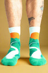 Green socks with white swan design and orange accents worn by a person on a white background