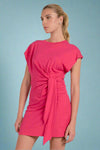 Woman wearing a pink dress with a tie detail on a white background