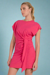 Woman wearing a pink dress with a tie detail on a white background