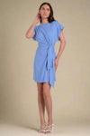 Woman wearing a light blue dress with a tie detail on a white background