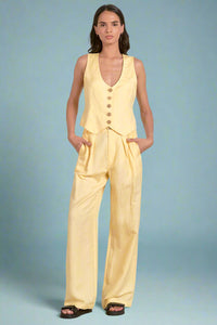 Woman wearing a yellow sleeveless top and pants set on a white background