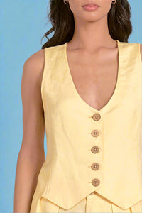 Yellow sleeveless top with buttons on a plain background