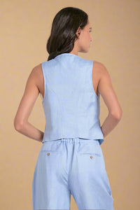 Woman wearing a light blue sleeveless top and pants set on a white background