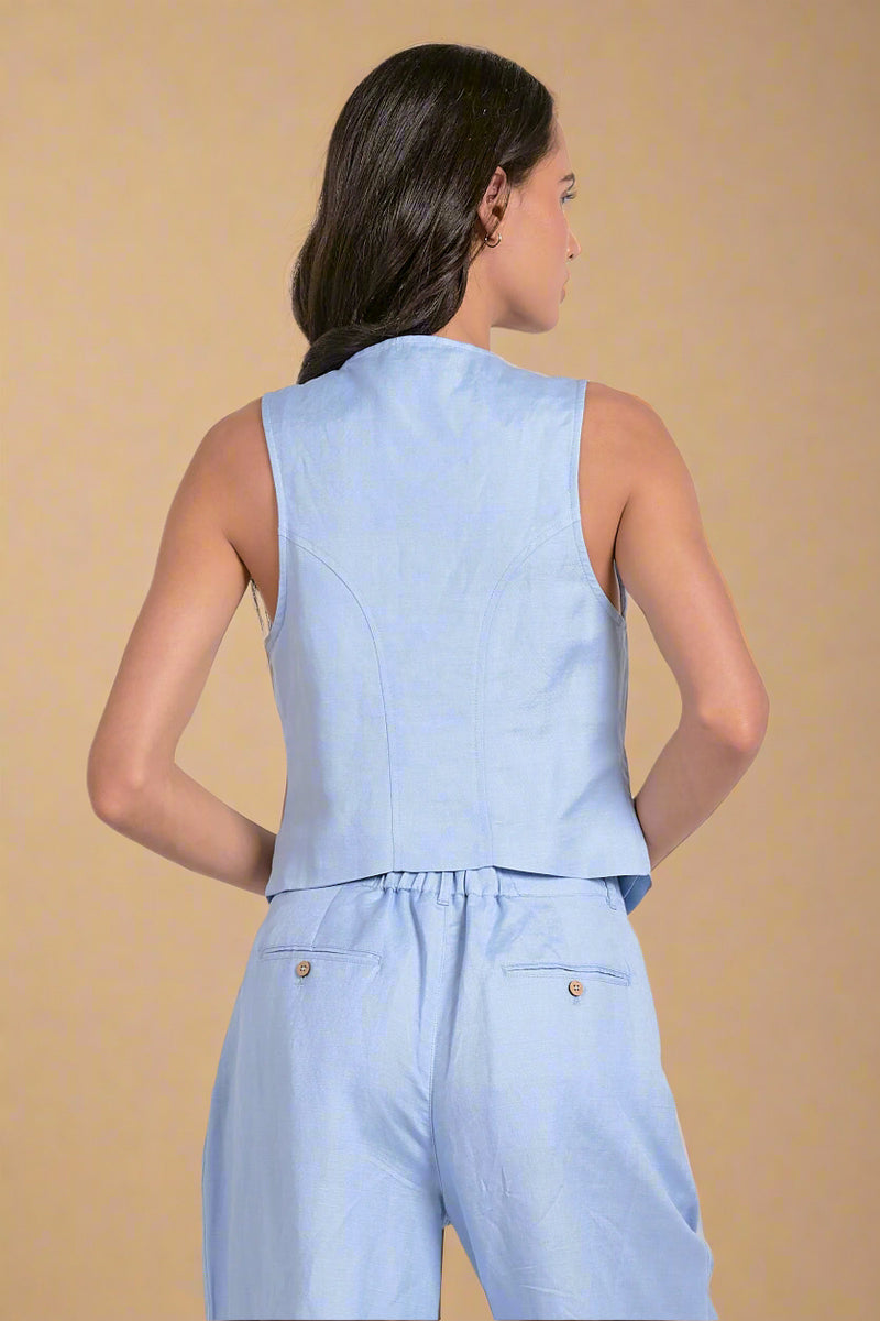 Woman wearing a light blue sleeveless top and pants set on a white background