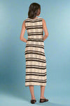 Woman wearing a sleeveless knit dress with black and white striped pattern on a plain background