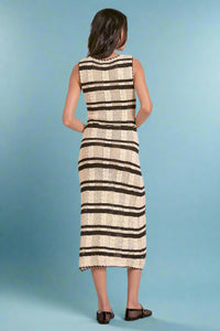 Woman wearing a sleeveless knit dress with black and white striped pattern on a plain background