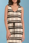 Woman wearing a sleeveless knit dress with black and white striped pattern on a plain background