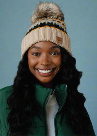 Woman wearing a knitted hat with a pom-pom against a dark background