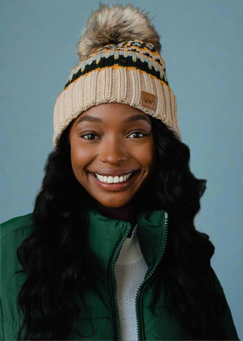 Woman wearing a knitted hat with a pom-pom against a dark background
