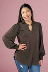 Woman wearing a brown blouse and blue jeans against a white background