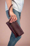 Model is holding a quilted fold-over wristlet clutch with zipper closure. 