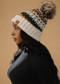 Woman wearing a patterned knit beanie with a pom-pom on a black background