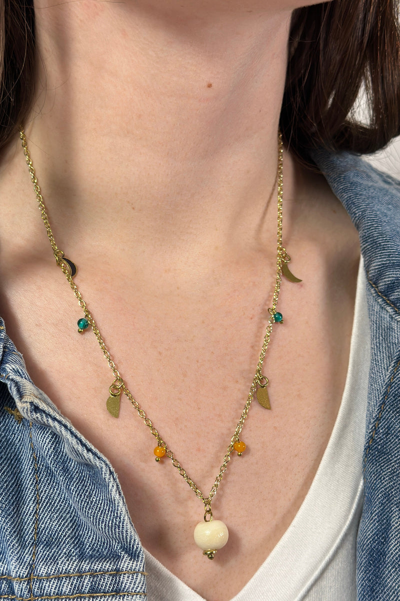 Model is wearing a gold necklace with varied celestial charms. 