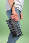 Model is holding a quilted fold-over wristlet clutch with zipper closure. 