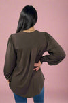 Person wearing a brown long-sleeve top with a plain background.