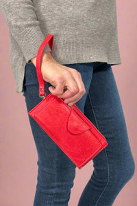 Model is holding a red colored wallet that doubles as a wristlet. 