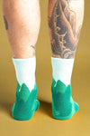 Green and white socks worn by a person with tattoos on a white background