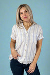 Model is wearing a short sleeved drop shoulder button up linen blend white top with faint blue striping.