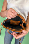 Model is carrying a small circle purse with braided handle, gold keychain and exterior pockets. Includes a cross body strap. 