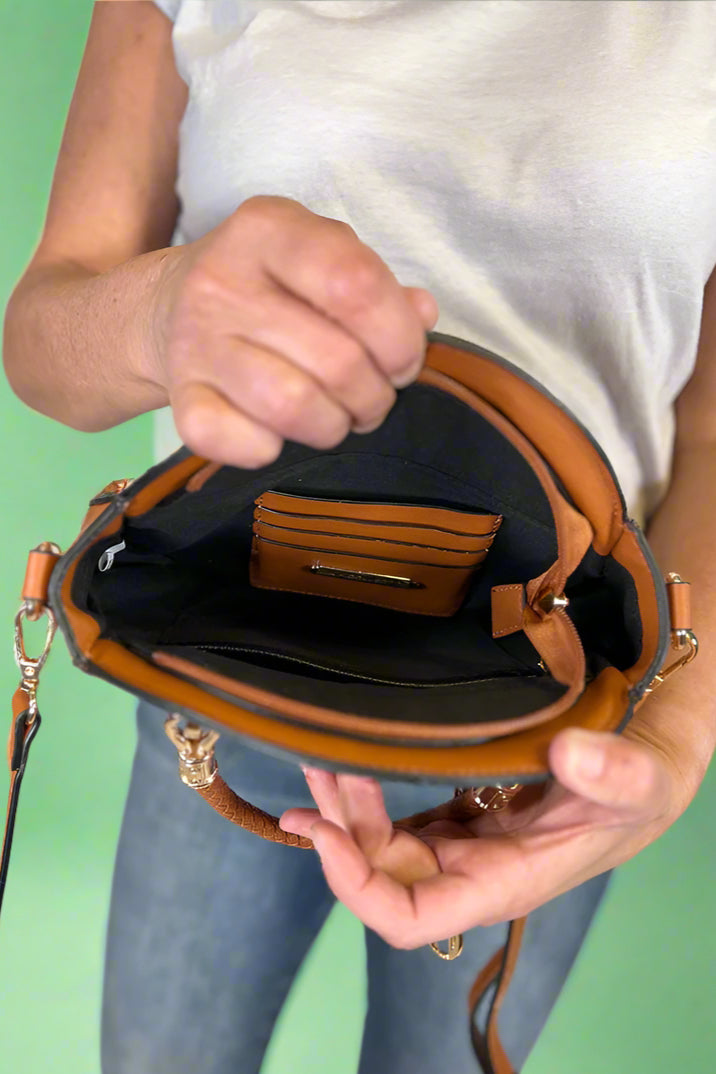 Model is carrying a small circle purse with braided handle, gold keychain and exterior pockets. Includes a cross body strap. 