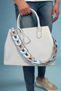 Model is carrying a large satchel with removable colorful woven strap. 