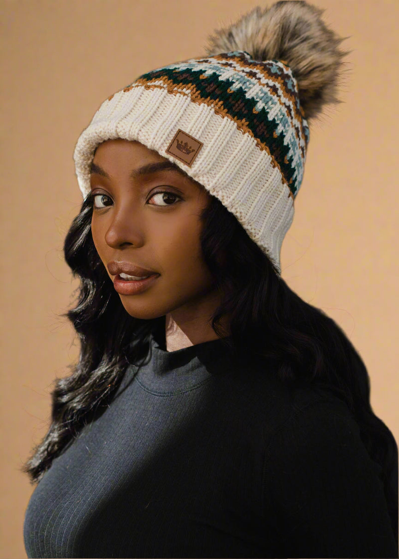 Woman wearing a patterned beanie with a pom-pom against a black background