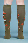 Green knee-high socks with mushroom pattern worn by a person on a white background