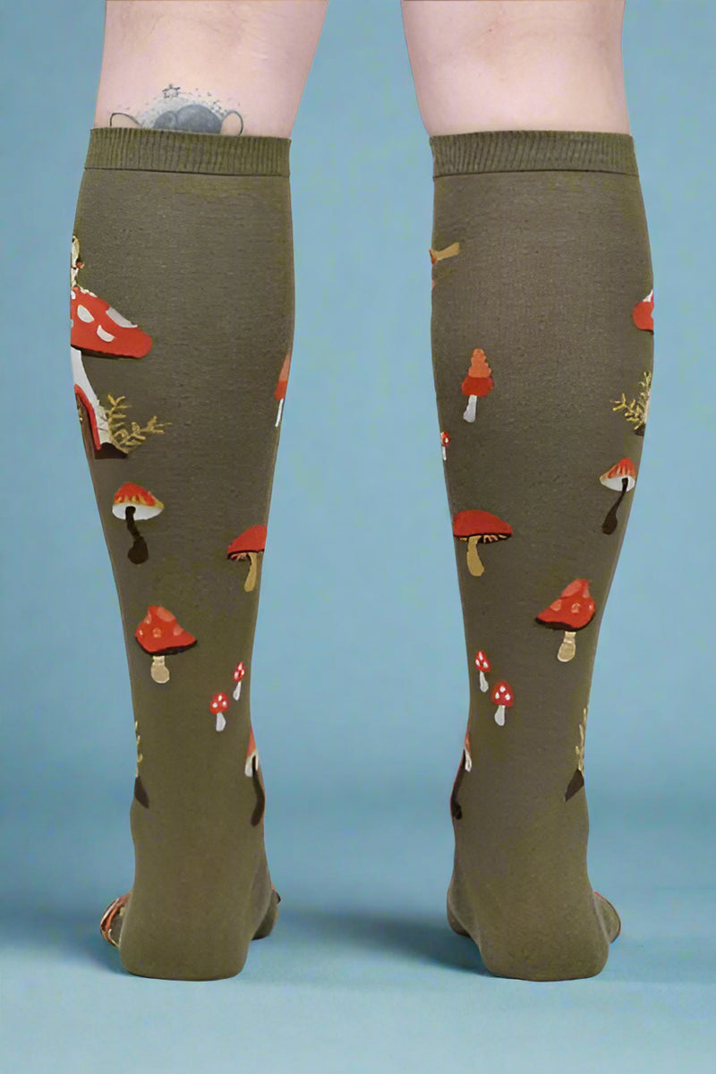 Green knee-high socks with mushroom pattern worn by a person on a white background