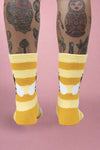 Yellow and white striped socks worn with tattoos on a white background