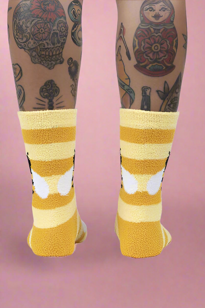 Yellow and white striped socks worn with tattoos on a white background