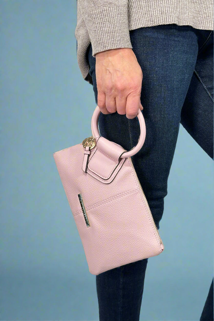 Model is holding a light pink colored wristlet that features card organization pockets. 