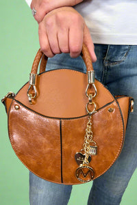 Model is carrying a small circle purse with braided handle, gold keychain and exterior pockets. Includes a cross body strap. 