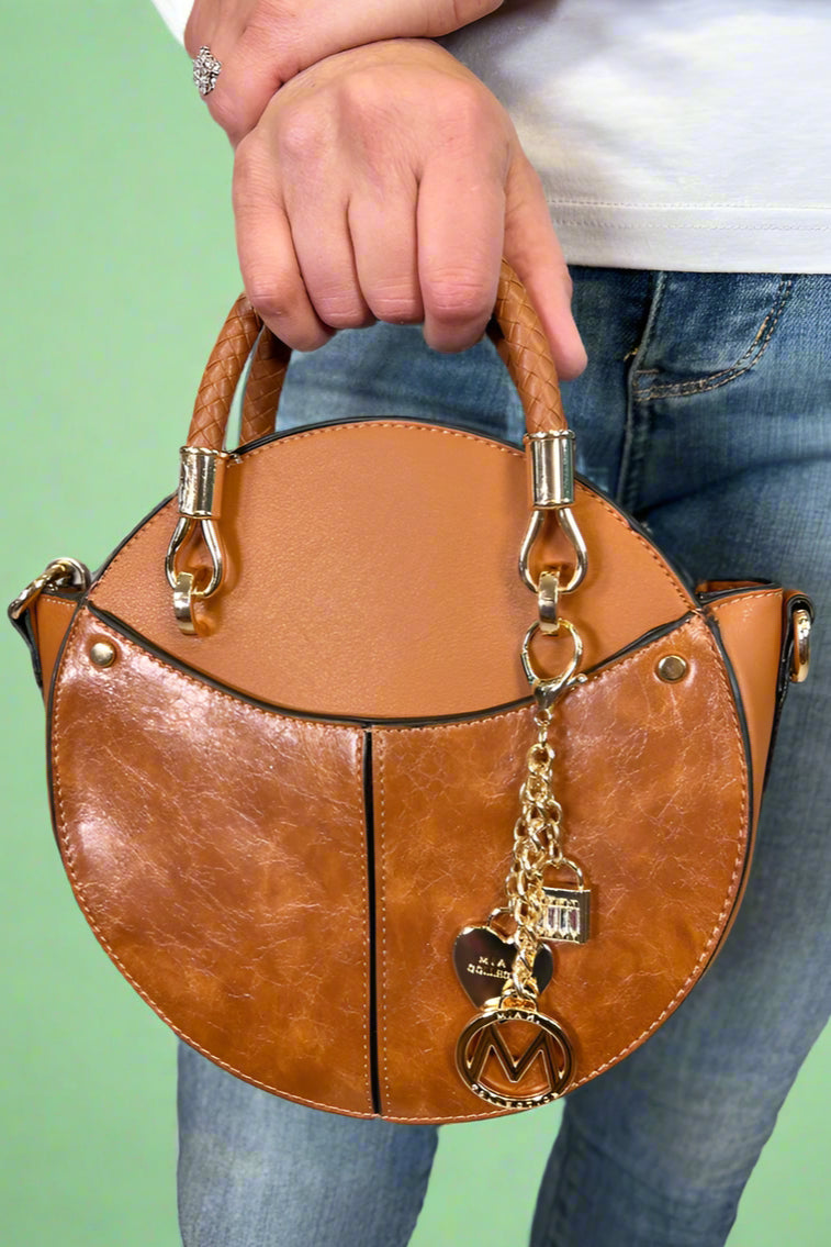 Model is carrying a small circle purse with braided handle, gold keychain and exterior pockets. Includes a cross body strap. 