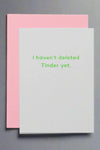 A greeting card with solid off-white front and bright green text that reads ‘I haven’t deleted Tinder yet.’