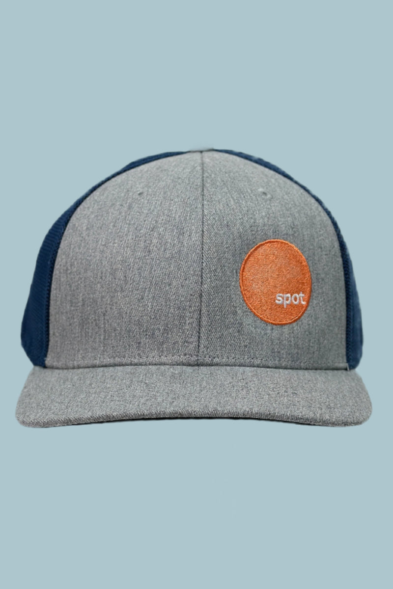 Heather grey colored trucker hat with a contrasting navy mesh back and an embroidered Spot logo.