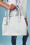 Model is carrying a large satchel with removable colorful woven strap. 