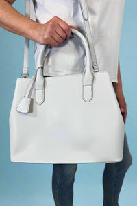Model is carrying a large satchel with removable colorful woven strap. 