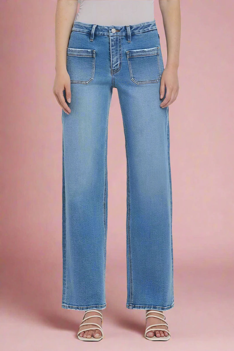 Person wearing straight leg blue jeans on a plain background.