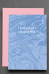 A greeting card with blue swirl front and white text that reads ‘I felt obliged to send this.’