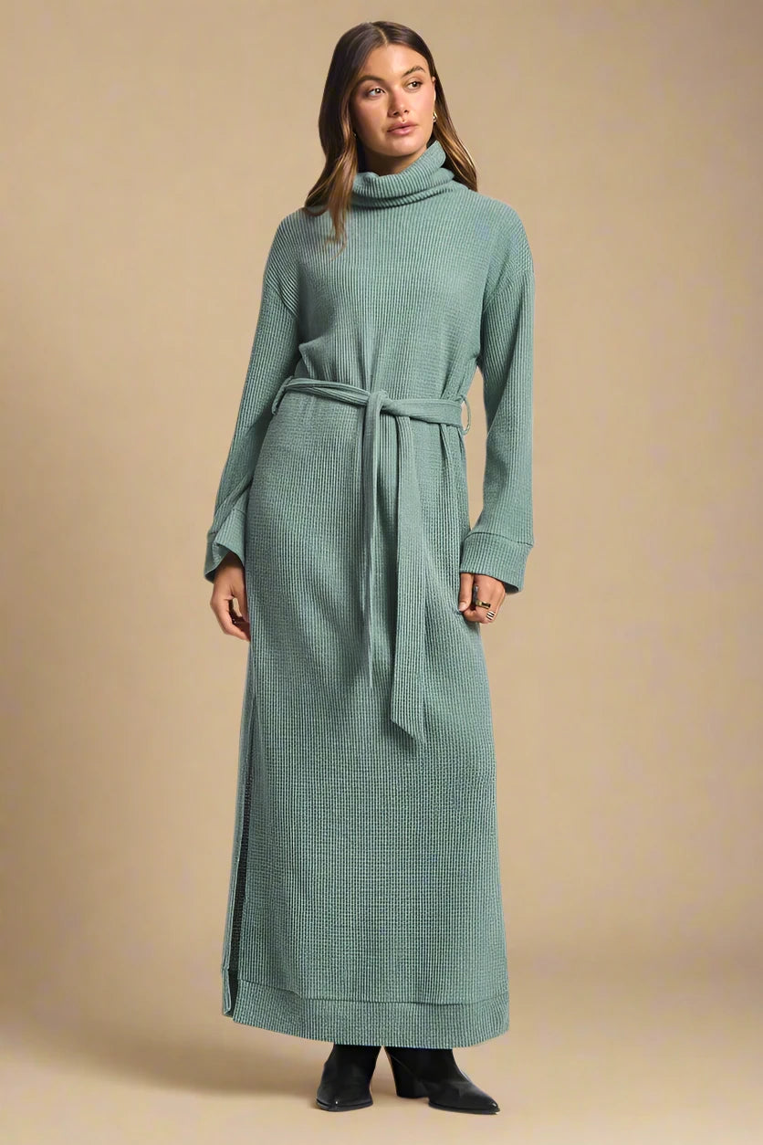 Woman wearing a long green dress with a belt on a white background