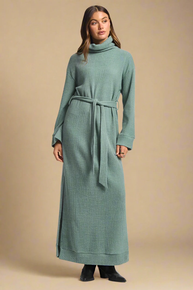 Woman wearing a long green dress with a belt on a white background