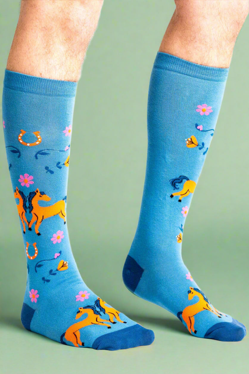 Blue socks with horse and floral patterns worn by a person on a white background