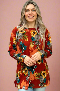 This crew neck long sleeve top is a rust color with a floral pattern. It is an oversized, relaxed fit.