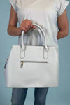 Model is carrying a large satchel with removable colorful woven strap. 