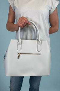 Model is carrying a large satchel with removable colorful woven strap. 