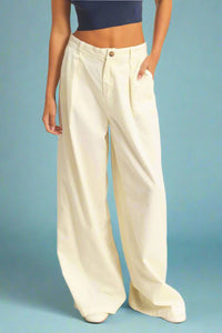 Model is wearing slouchy cream colored trousers