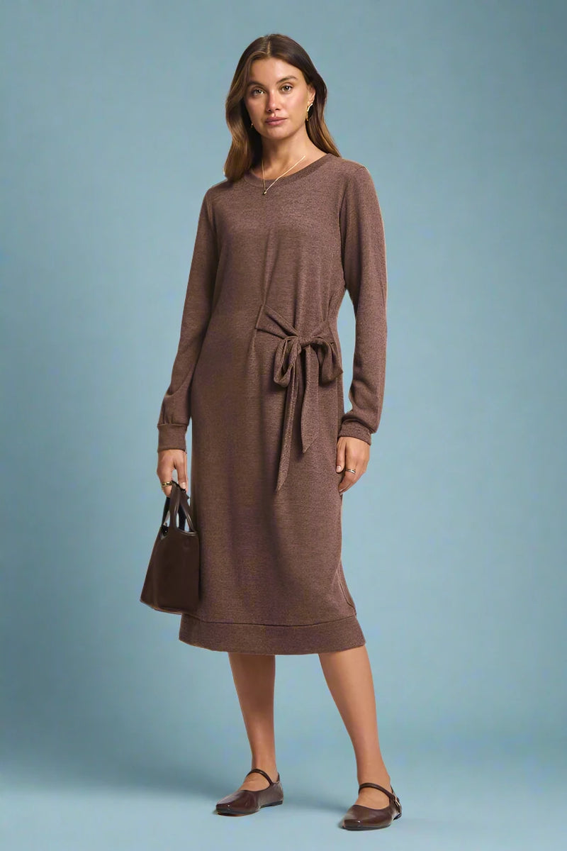 Woman wearing a brown dress with a belt on a plain background